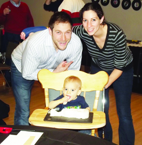 FIRST BIRTHDAY MITZVAH PROJECT — The birth of last year’s first Jewish baby Gabriel Goodbinder was celebrated at the JFS Food Pantry. Gabriel’s guests donated more than 200 pounds of food to the pantry (which they weighed themselves as part of the volunteer experience) that is expected to feed about nine families. They also filled boxes of food to be delivered and “shopped” for clients who are unable to get to the pantry themselves. As a reward for their service time, guests enjoyed birthday treats at the Jewish Community Campus. Shown here celebrating with Gabriel as he eats his guitar-shaped cake baked by his mother are his parents, Jay and Darcy Goodbinder.